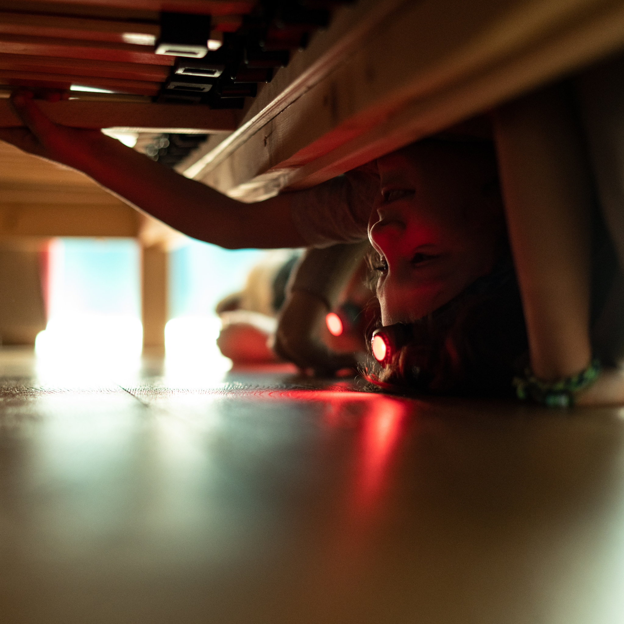 Kidled2 Headlamp worn by child under a table headlamp emitting red light on the floor