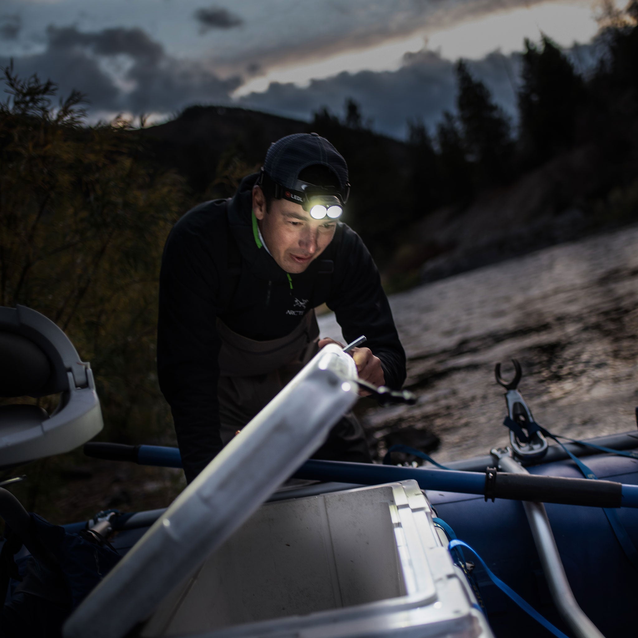 H19R Core Headlamp worn by a person in black outdoors at dusk with dual LEDs lit leaning over gear on a boat