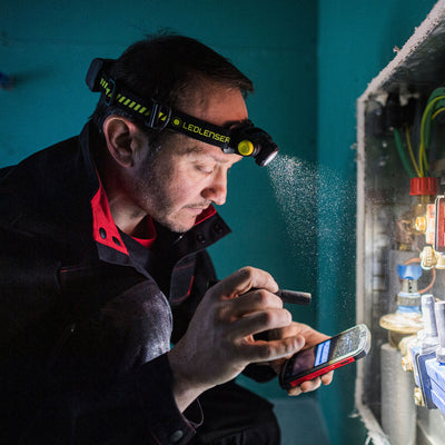 P2R Work Torch headlamp worn by a worker with a blue Ledlenser strap inspecting an electrical panel indoors