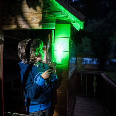 Ledlenser Kidbeam4 Torch held by a child on a wooden cabin porch with a green glow on the wall