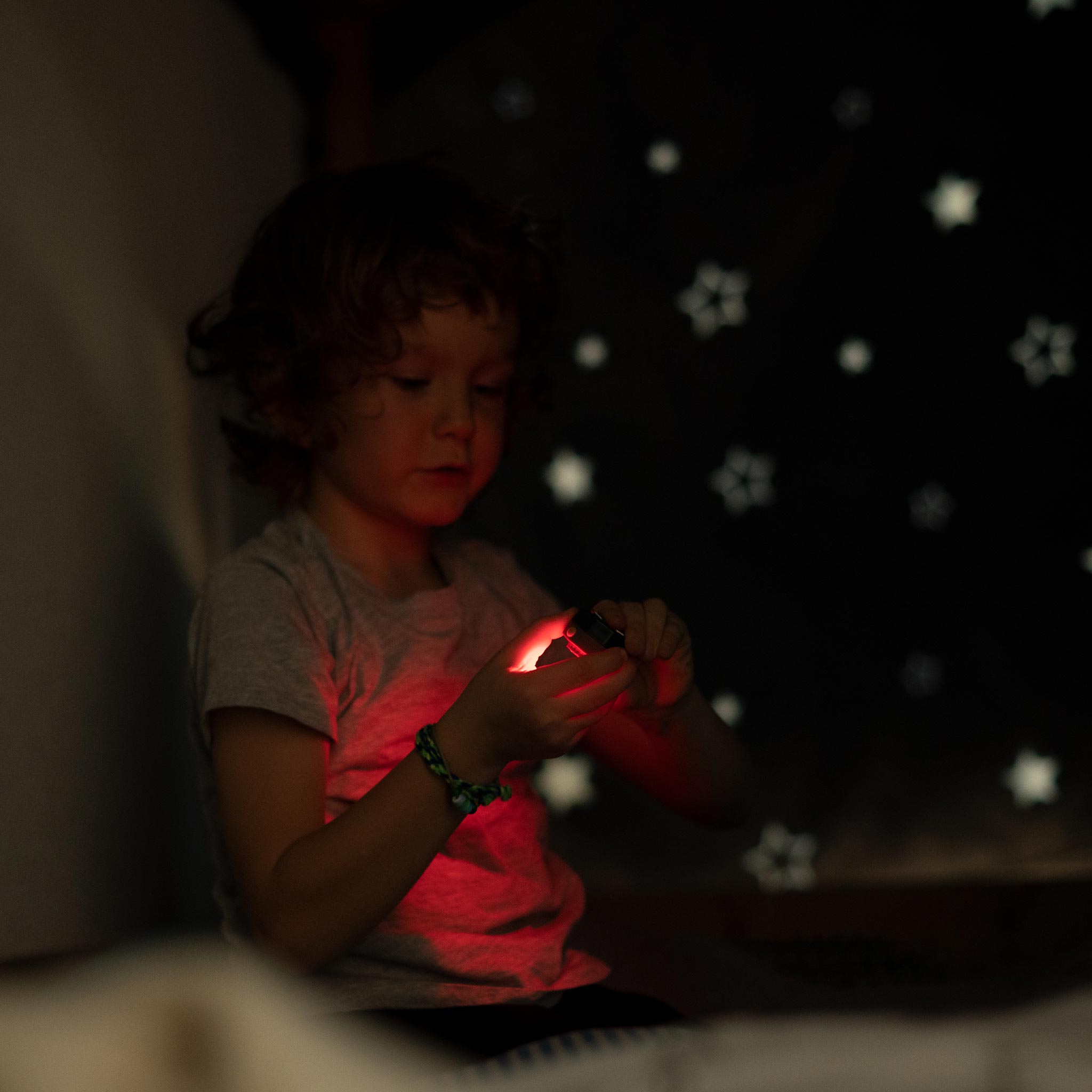 Ledlenser Kidled4R Headlamp held by a child in a dim room with the red light visible on the device