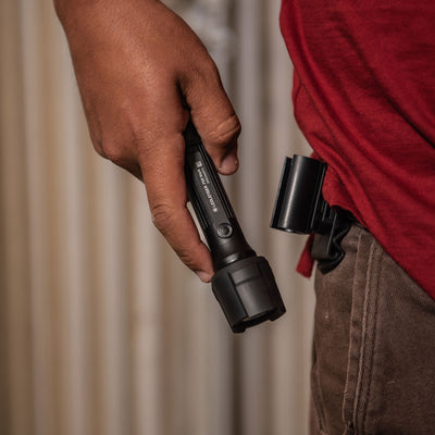 Ledlenser P5R Work Torch held in a right hand compact black flashlight with textured grip and belt holster on the wearer
