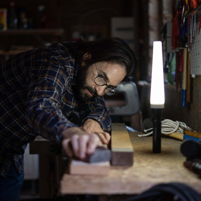 Signal Cone W 53mm placed on a workshop workbench as a man sands wood with a tall LED lamp nearby