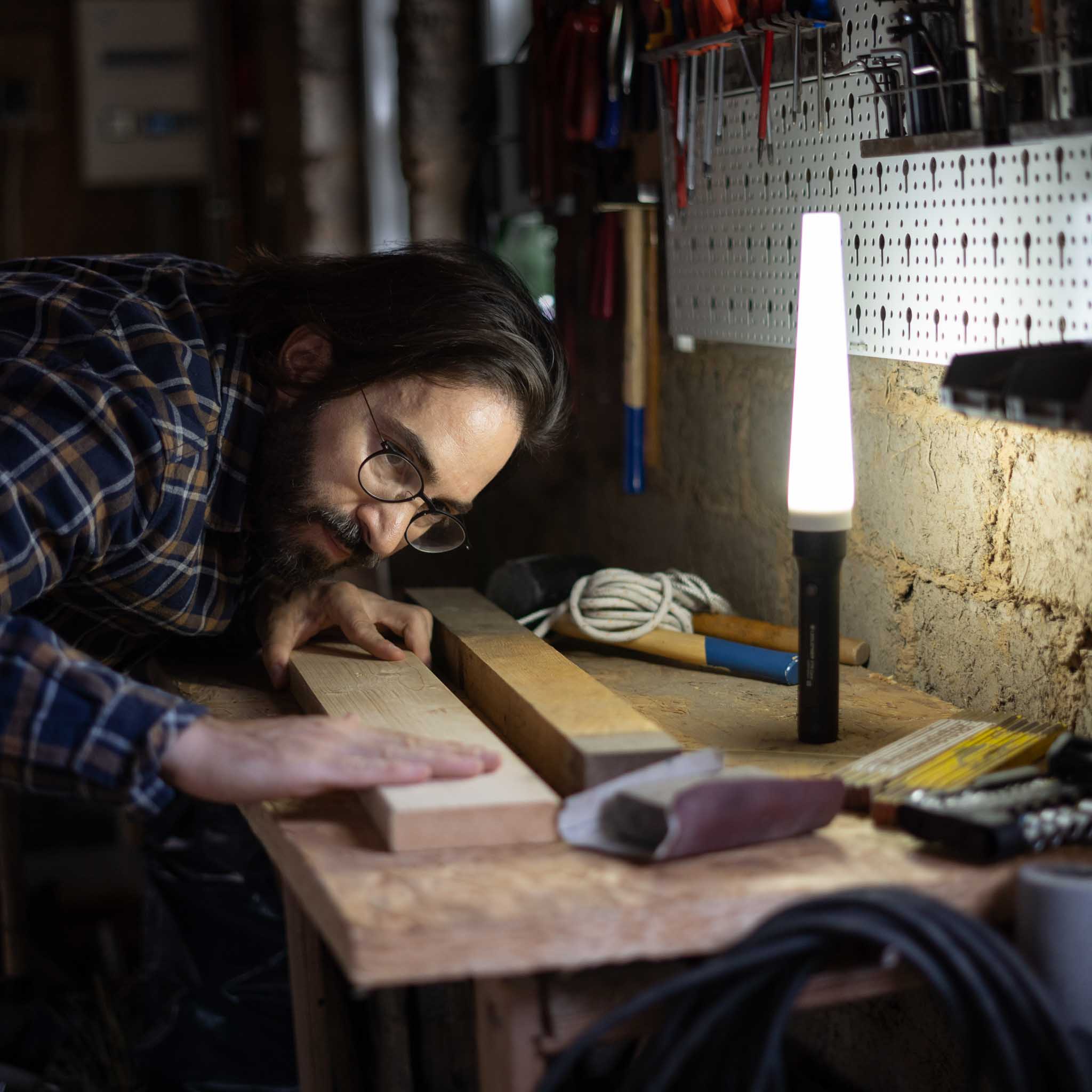 Ledlenser Signal Cone W 42mm product image showing a man at a woodwork bench with a tall lamp on the bench in a workshop