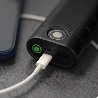 Ledlenser Flex10 Powerbank close up of black portable charger with white USB C cable plugged into IN port showing OUT and IN ports and green power button visible