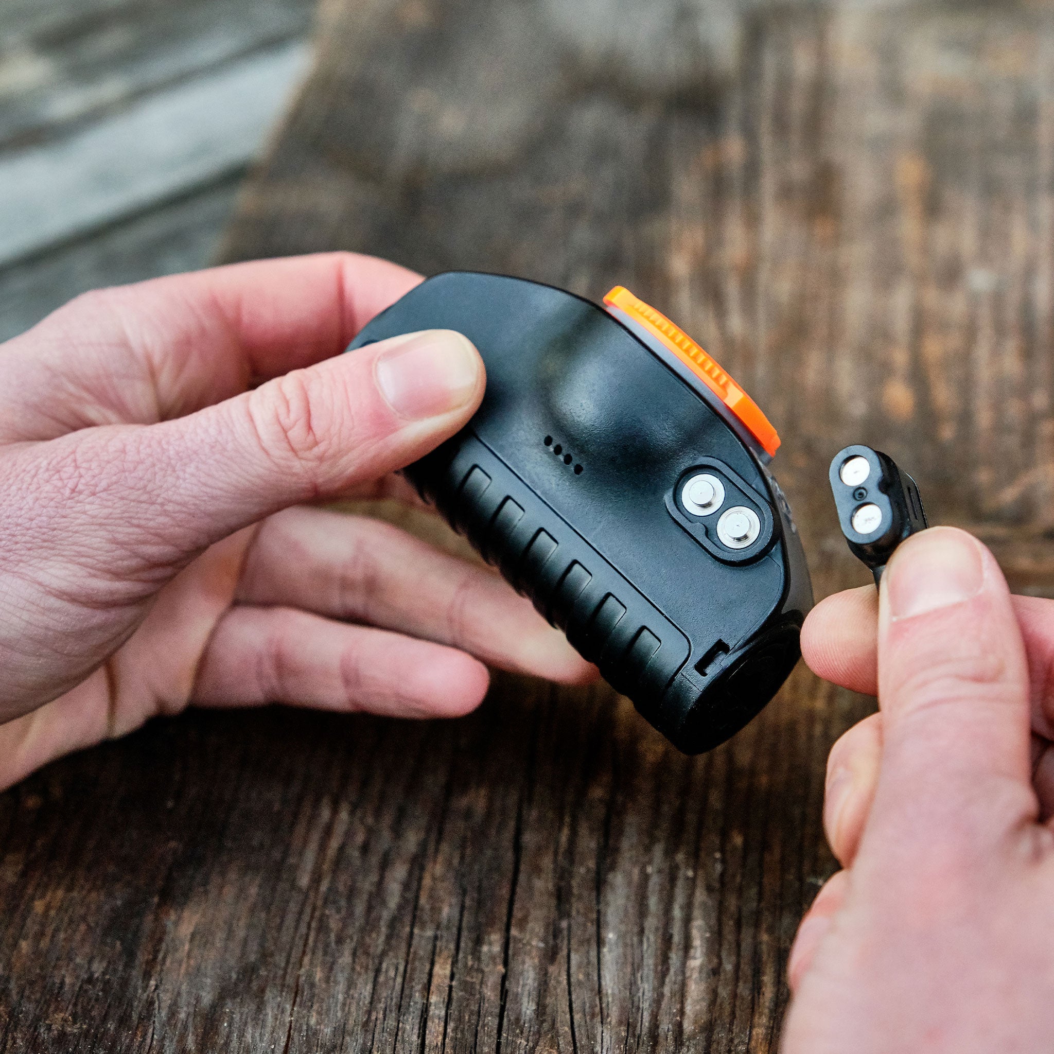 MH11 Outdoor Headlamp by Ledlenser black compact headlamp with orange bezel hands removing the detachable battery module