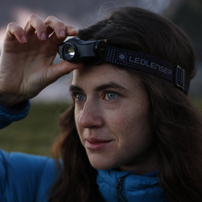 MH3 Headlamp worn by a person adjusting the light; black Ledlenser headband with a dotted pattern