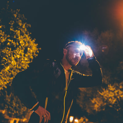 Ledlenser NEO6R Rechargeable Headlamp worn by a man outdoors at night with a bright beam in a dark background