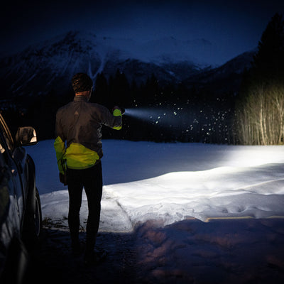 Ledlenser P18R Signature Torch in use outdoors at night with a person shining the beam across a snowy landscape