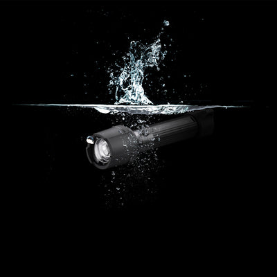 Ledlenser P7R Work UV Torch angled left black cylindrical rechargeable flashlight submerged in water with splash around the head