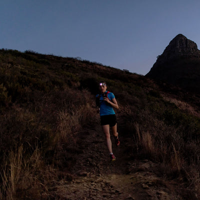 SEO5 Headlamp worn by a runner on a rocky trail at dusk with a headlamp illuminating the path