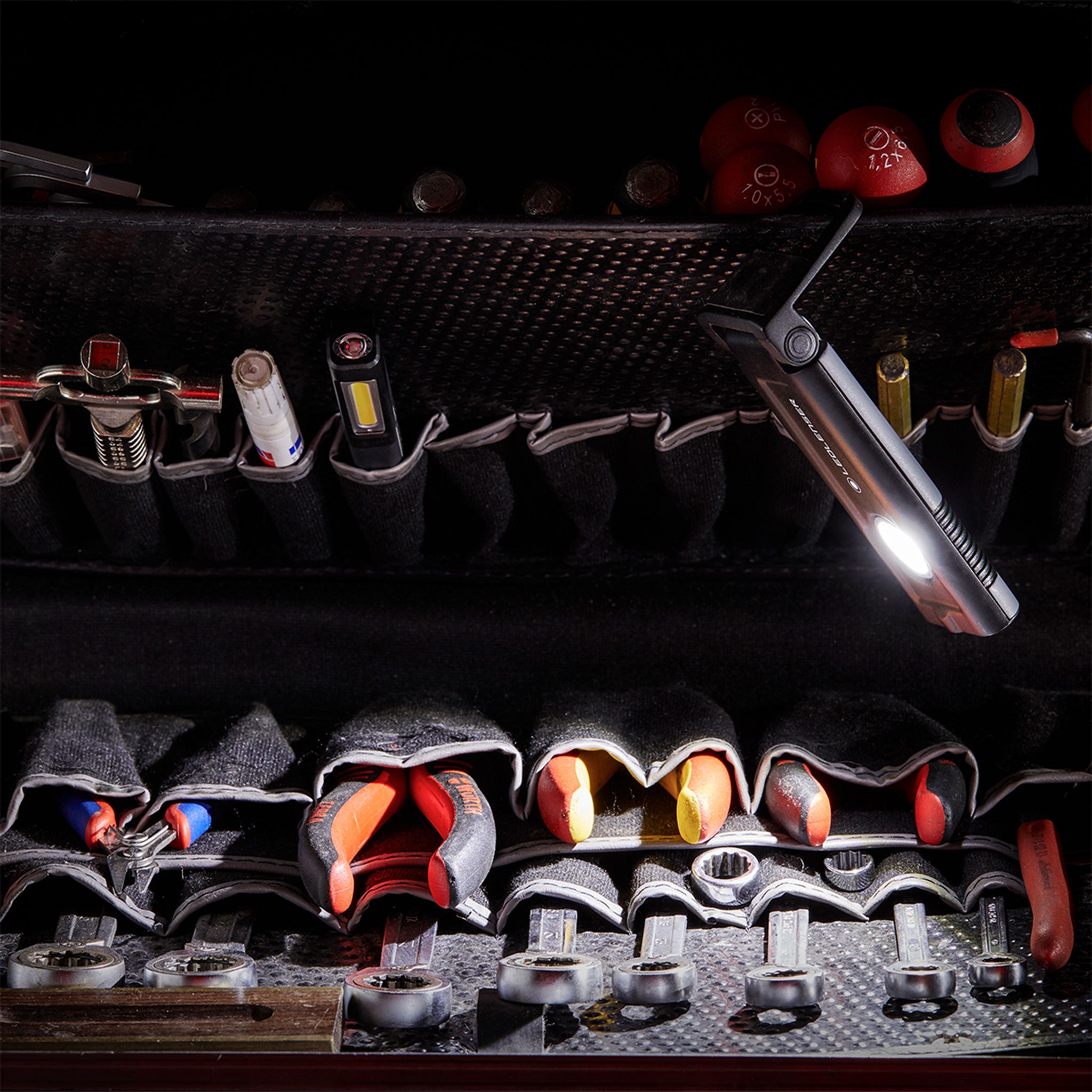 iF2R Spotlight compact rechargeable floodlight in a black tool roll with wrenches and sockets; light on