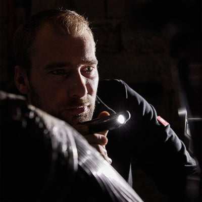 iF2R Spotlight handheld LED torch held by a man in a dark setting with the compact light on