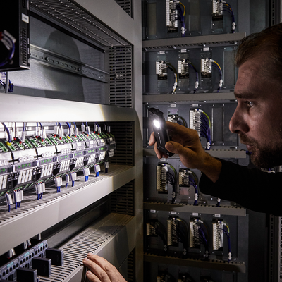 Ledlenser iF2R Spotlight handheld flashlight being tested near an electrical control panel with wiring and terminal blocks