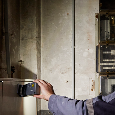Ledlenser iF3R Spotlight held by a hand in an industrial workshop beside a wall panel and electrical enclosure