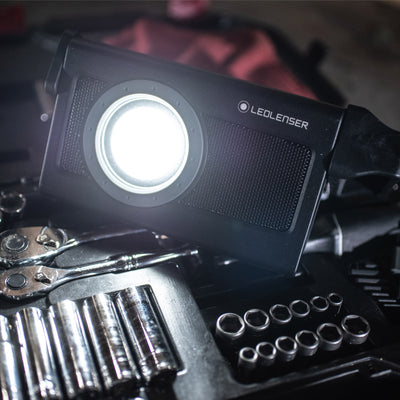 Ledlenser iF4R Music Spotlight in black with a circular front lens resting on a toolbox with sockets and wrenches visible