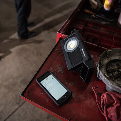 Ledlenser iF4R Music Spotlight on a red workbench with a round LED head and built in stand next to a smartphone
