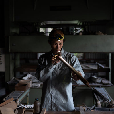 iH9R Headlamp worn by a craftsman in a dim workshop headlamp active as he inspects a wooden tube
