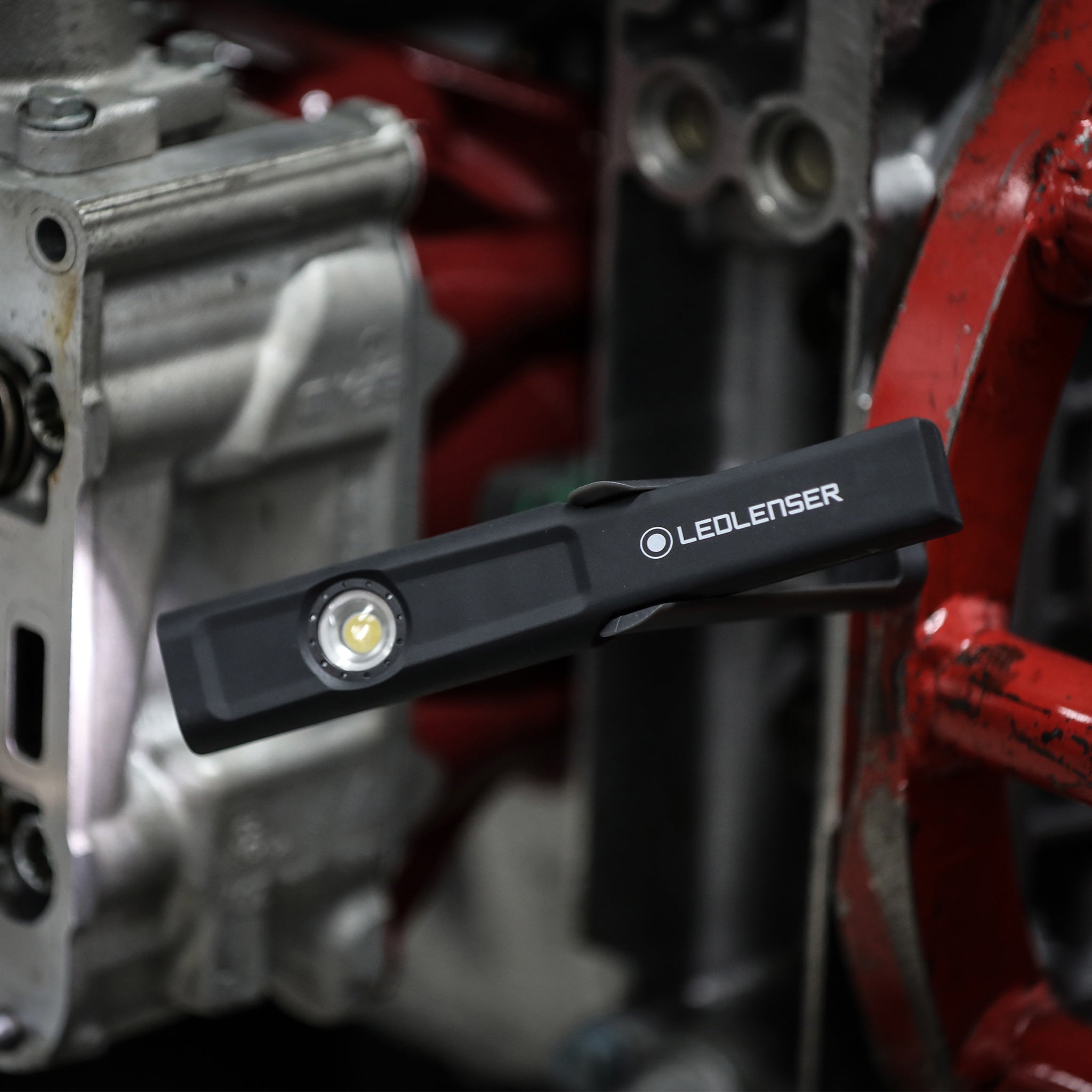 iW4R Work Light by Ledlenser mounted on industrial machinery; compact black rechargeable work light with logo visible