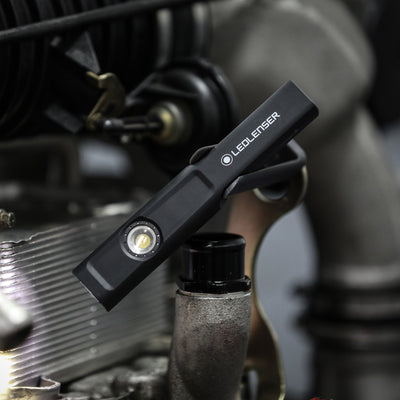iW4R Work Light by Ledlenser mounted on machinery surface with a clip attachment black compact handheld work light
